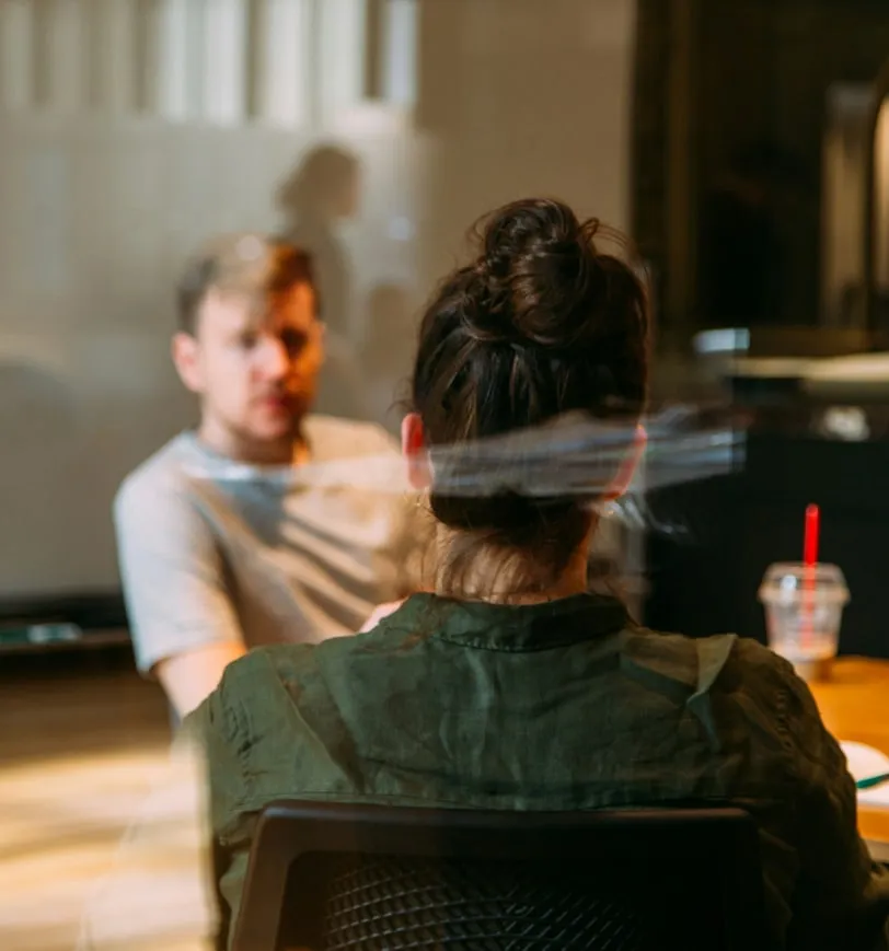 a man and a woman sitting at a table in front of a projector screen